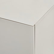 Nahaufnahme der oberen Ecke eines weißen, minimalistischen Möbelkorpus mit glatter Oberfläche, aufgenommen aus schräger Oberperspektive