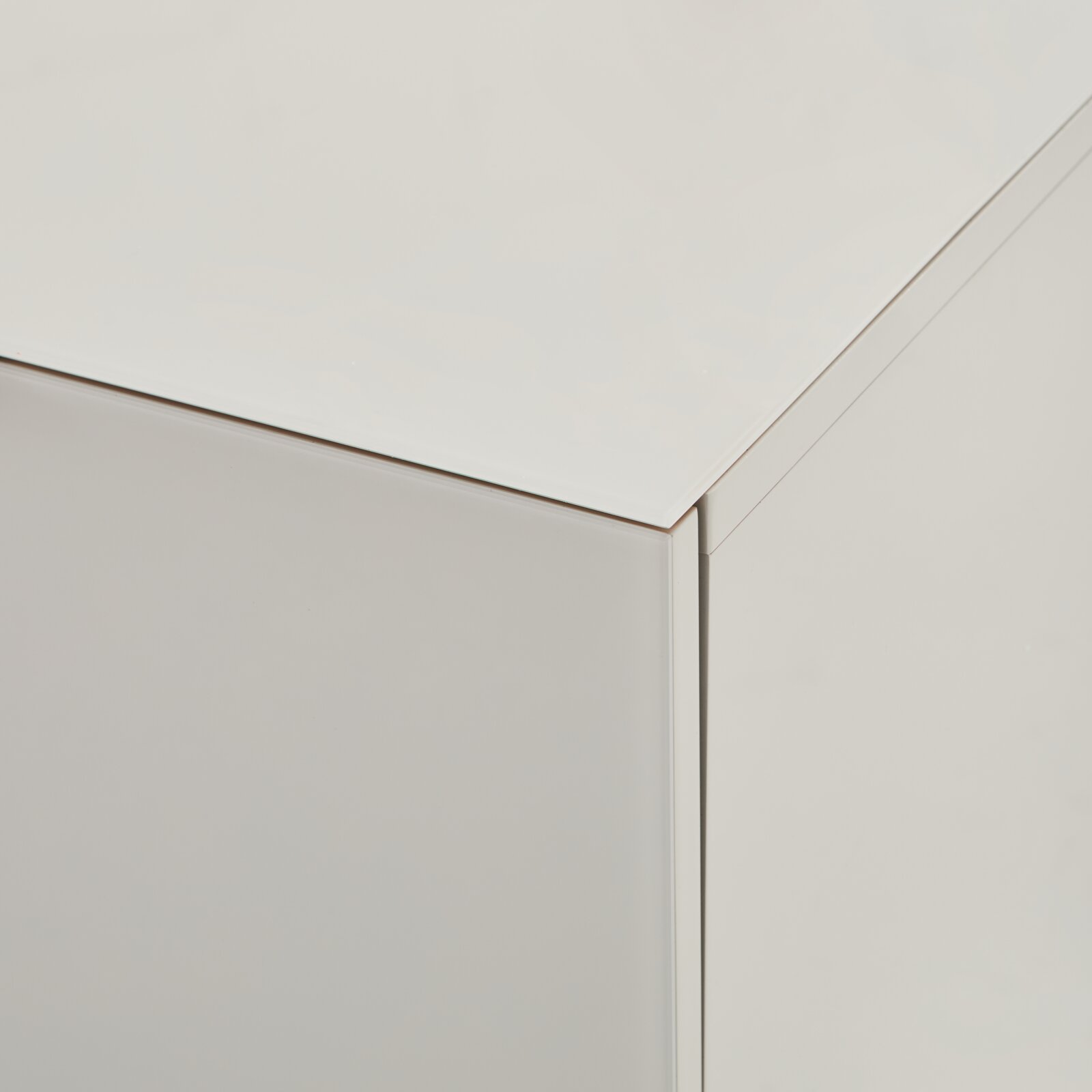 Nahaufnahme der oberen Ecke eines weißen, minimalistischen Möbelkorpus mit glatter Oberfläche, aufgenommen aus schräger Oberperspektive