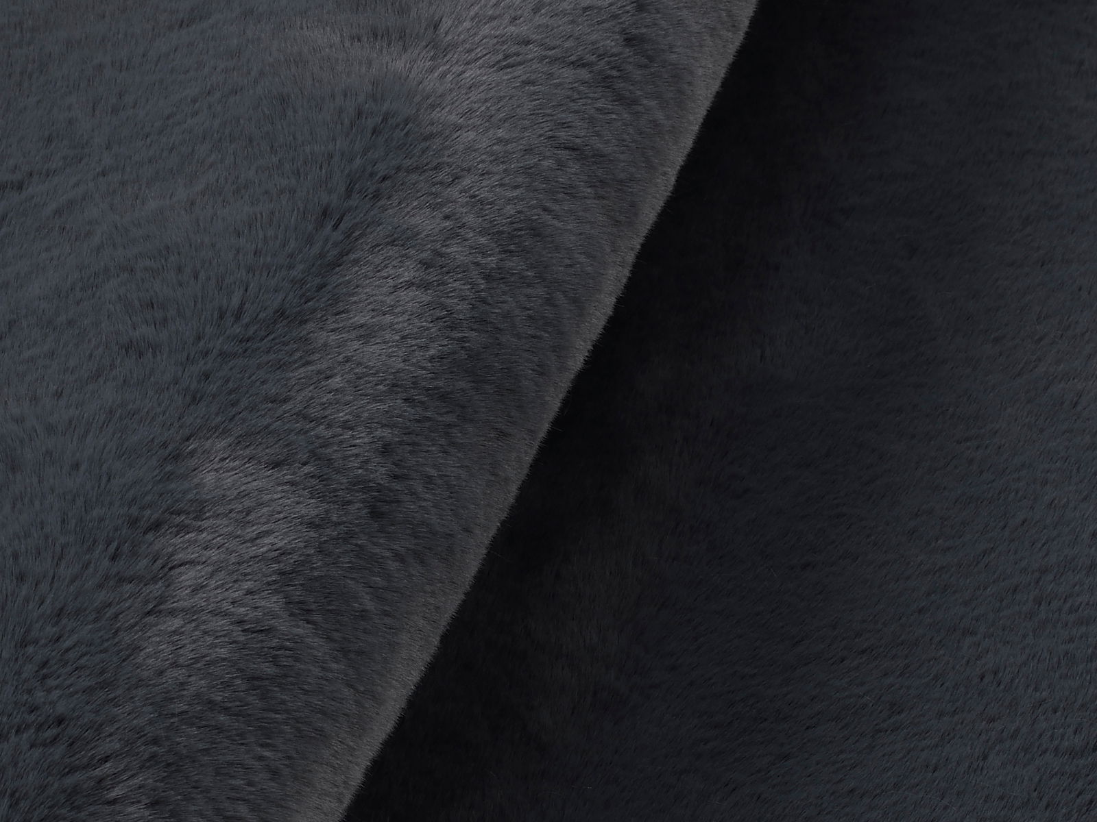 Nahaufnahme eines dunkelgrauen Fellteppichs mit weicher Textur, seitliche Perspektive
