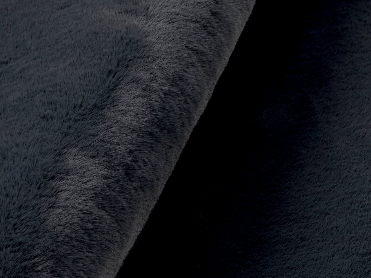 Nahaufnahme eines dunkelgrauen Fellteppichs mit weicher Textur, seitliche Perspektive