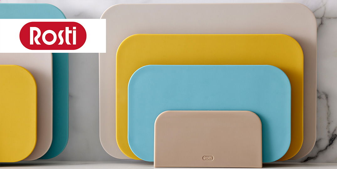 Mehrere bunte Schneidebretter in verschiedenen Größen stehen an einer Wand mit Marmoroptik.