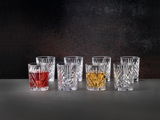 Set aus acht Kristallgläsern mit elegantem Schliffmuster, gefüllt mit verschiedenen Getränken, auf einer dunklen Oberfläche vor schwarzem Hintergrund, aus frontaler Perspektive.