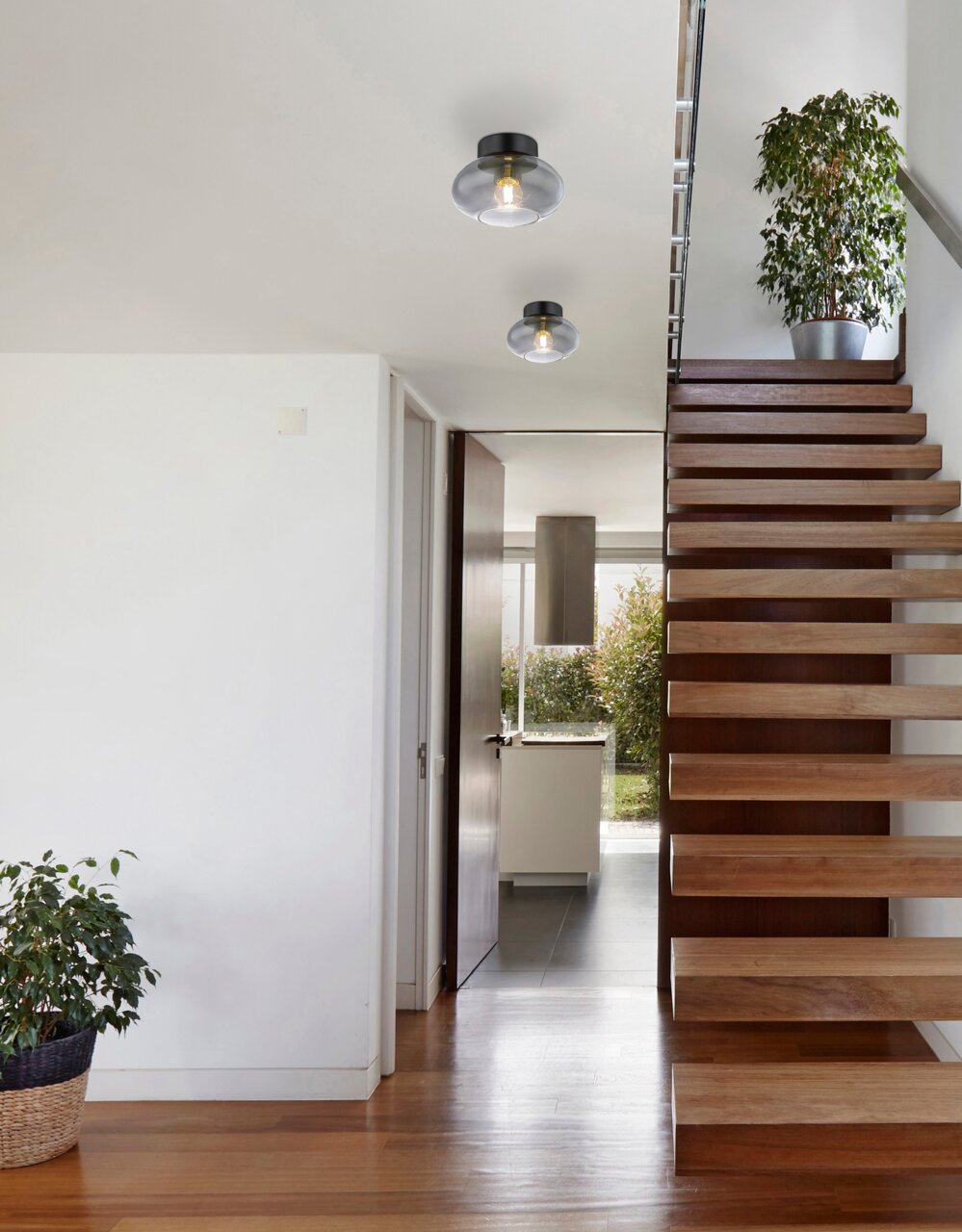 Moderne Deckenleuchte in einem Flur mit Holztreppe, aus der Perspektive von unten betrachtet.