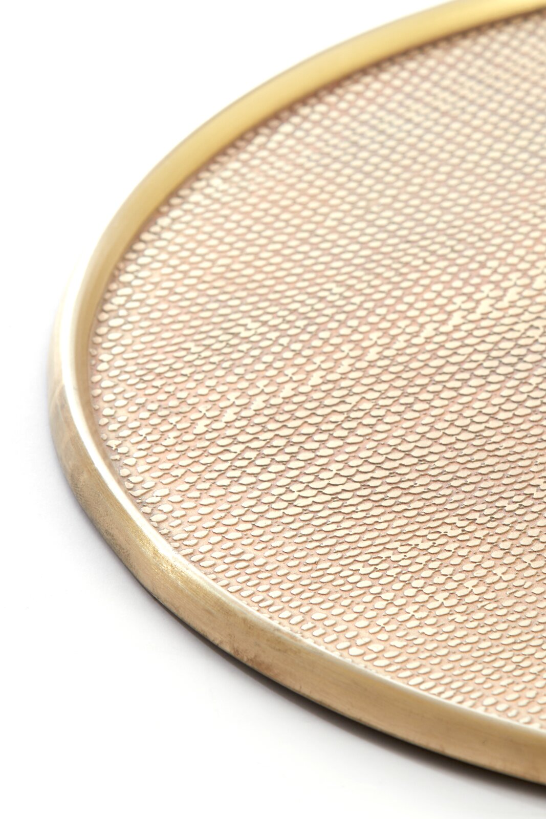 Detailaanzicht van bovenaf van een ronde goudkleurige schaal met verhoogde rand en fijn reliëfpatroon