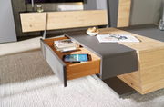 Moderner Couchtisch mit Holz- und Grauelementen, Schublade geöffnet, von schräg oben fotografiert.