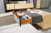 Moderner Couchtisch mit Holz- und Grauelementen, Schublade geöffnet, von schräg oben fotografiert.
