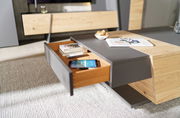 Moderner Couchtisch mit Holz- und Grauelementen, Schublade geöffnet, von schräg oben fotografiert.