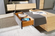 Moderne salontafel met houten en grijze elementen, met geopende lade, gefotografeerd vanuit een schuine hoek van bovenaf.