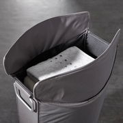 Grauer Wäschesammler mit geöffnetem Deckel, gefüllt mit Handtüchern, aus der Vogelperspektive.