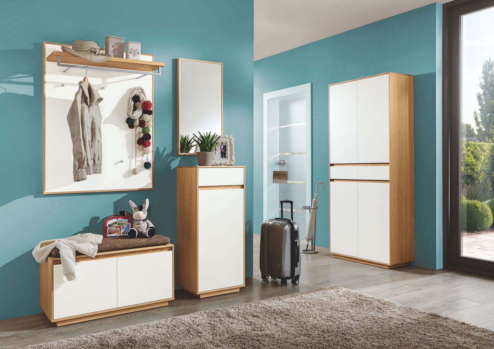 VOSS Sitzkissen V100 Moderne Garderobeneinrichtung mit Garderobenbank, Sitzkissen, Garderobenpaneel, Schuhschrank und Spiegel in einem hellen Raum mit blauer Wand. Perspektive von vorne.