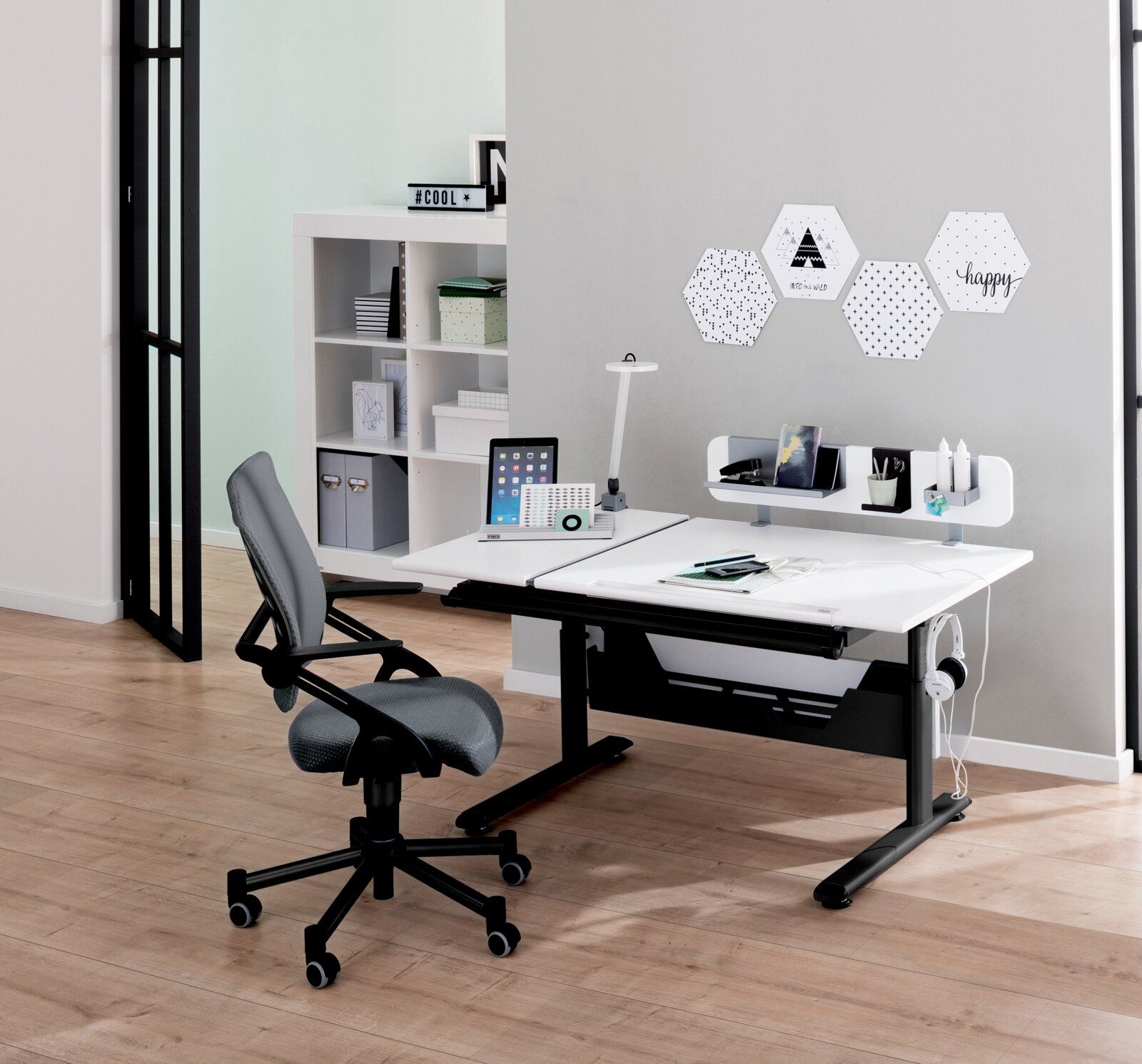Moderner Schreibtisch mit ergonomischem Bürostuhl, seitliche Perspektive, ausgestattet mit Laptop, Lampe und Wanddekoration.