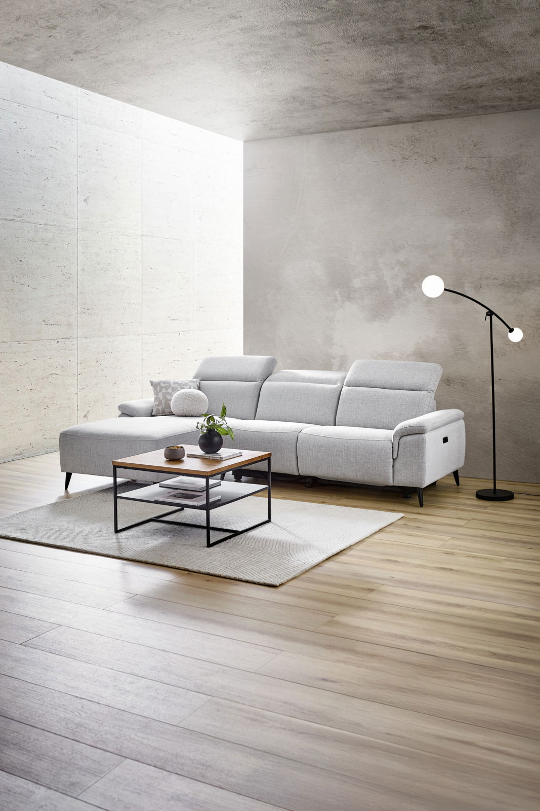 Moderne Longchairkombination in hellem Grau, seitliche Perspektive, mit verstellbaren Kopfstützen, Couchtisch und Stehlampe in einem stilvollen Wohnzimmer.