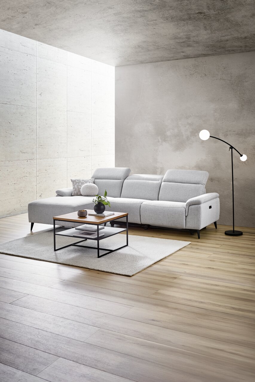 Moderne Longchairkombination in hellem Grau, seitliche Perspektive, mit verstellbaren Kopfstützen, Couchtisch und Stehlampe in einem stilvollen Wohnzimmer.