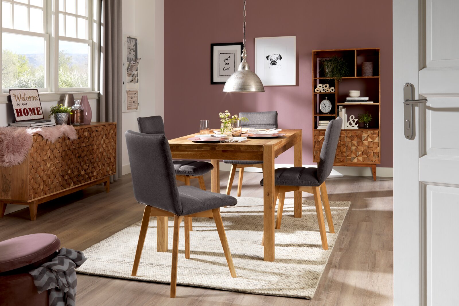 Linea Natura Esstisch TINA Esszimmer mit einem Holztisch und vier grauen Stühlen, umgeben von stilvoller Dekoration. Perspektive von der Tür aus.