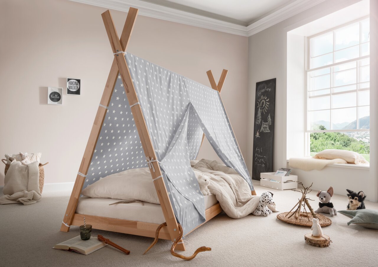 Houten tipi-bed met grijze stof met sterrenmotief, zijaanzicht, omringd door knuffels en decoratie in een lichte kinderkamer.