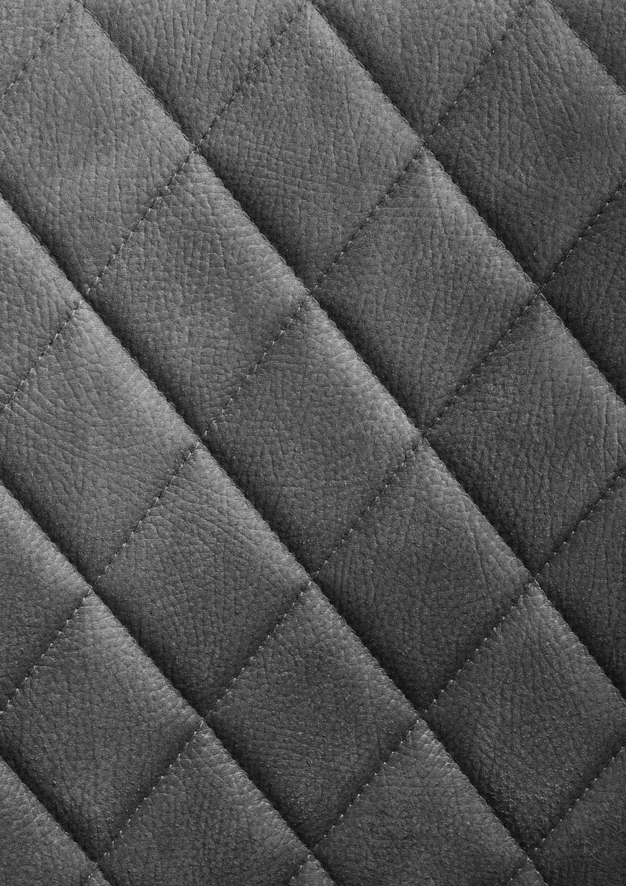 Nahaufnahme einer grauen, gesteppten Lederoberfläche in Rautenmuster.