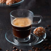 Espressotasse Senso 70ml aus Glas mit Untertasse, gefüllt mit heißem Espresso, seitliche Perspektive