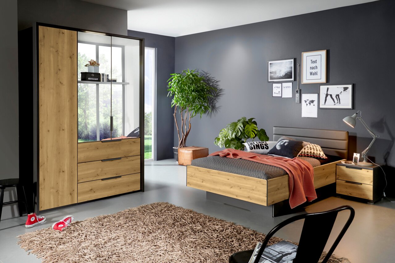 Modernes Schlafzimmer mit Bett, Nachttisch und Kleiderschrank in Holzoptik mit schwarzen Akzenten; Kleiderschrank mit Glasfront und Schubladen, Bett mit gepolstertem Kopfteil – Perspektive: frontale Raumansicht in leichter Schrägansicht von links.