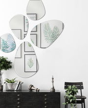 Facettenspiegel in organischen Formen an einer weißen Wand, umgeben von Pflanzen und Wandkunst, aus der Frontalperspektive betrachtet.