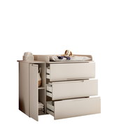 Beige Wickelkommode mit Wickelaufsatz, drei halb geöffneten Schubladen und seitlichem Regal, oben Wickelauflage mit Stofftier; Ansicht schräg von vorn links