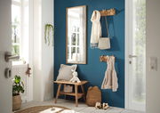 Eingangsbereich mit einer Garderobenbank aus Holz, einem Spiegel und Hakenleisten an einer blauen Wand. Perspektive von der Tür aus.