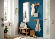 Eingangsbereich mit einer Garderobenbank aus Holz, einem Spiegel und Hakenleisten an einer blauen Wand. Perspektive von der Tür aus.