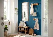 Eingangsbereich mit einer Garderobenbank aus Holz, einem Spiegel und Hakenleisten an einer blauen Wand. Perspektive von der Tür aus.