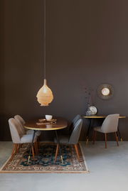 Moderner Esstisch mit vier Stühlen, dekoriert mit Geschirr und einer hängenden Lampe, aus der Frontalperspektive.