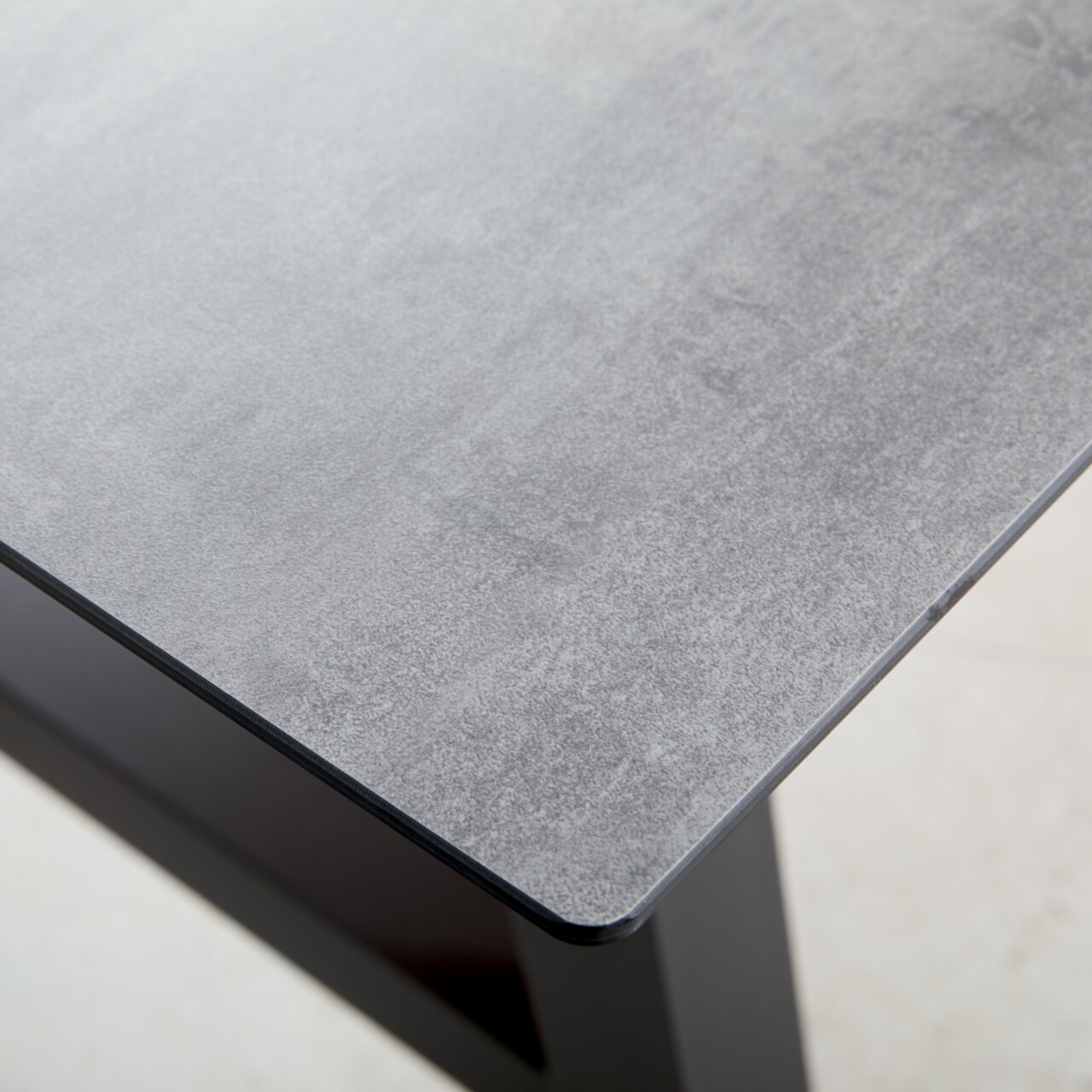 Nahaufnahme eines Gartentisches mit grauer Tischplatte und schwarzem Gestell, Perspektive von oben.