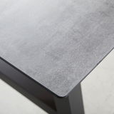 Nahaufnahme eines Gartentisches mit grauer Tischplatte und schwarzem Gestell, Perspektive von oben.