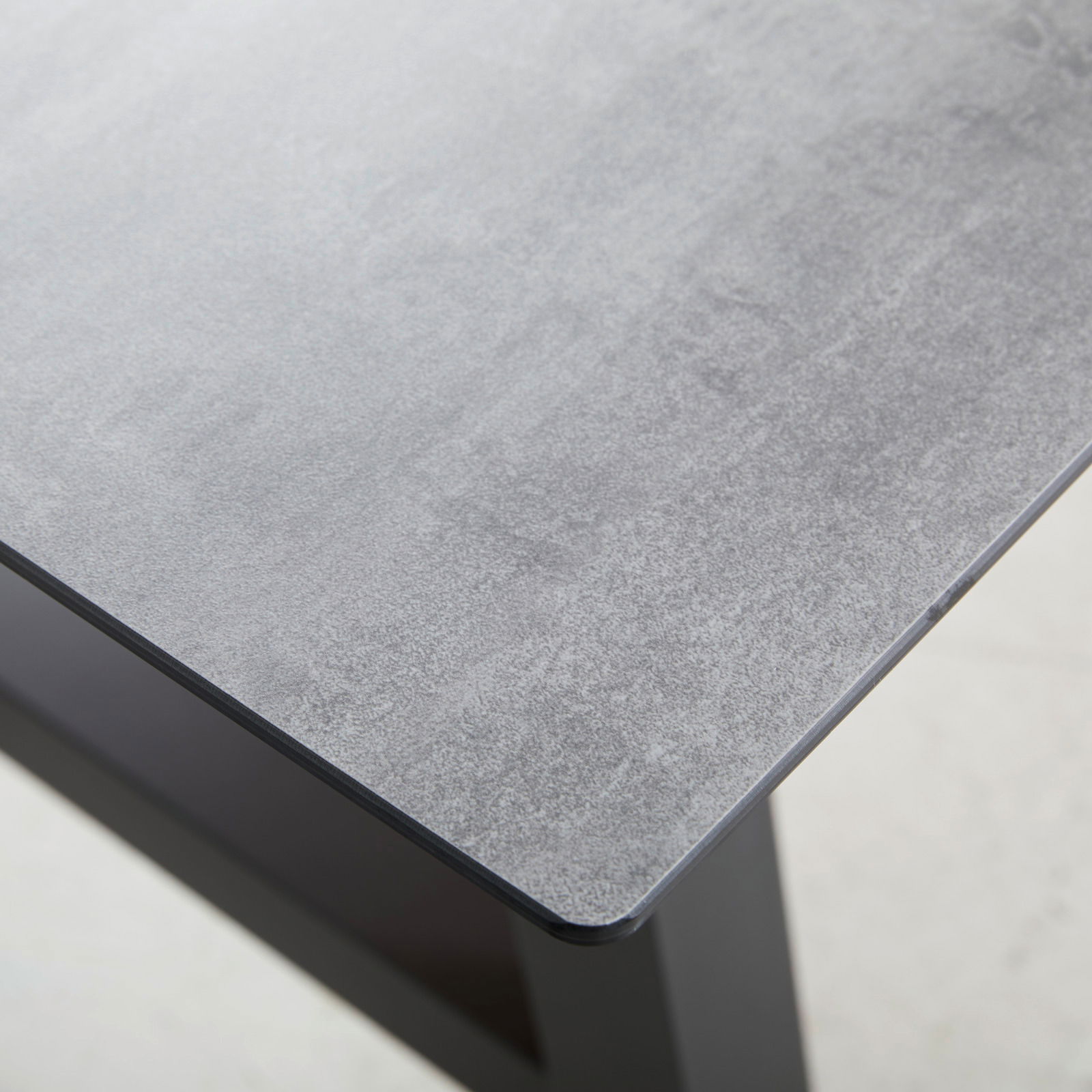 Nahaufnahme eines Gartentisches mit grauer Tischplatte und schwarzem Gestell, Perspektive von oben.