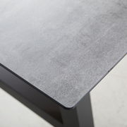 Nahaufnahme eines Gartentisches mit grauer Tischplatte und schwarzem Gestell, Perspektive von oben.