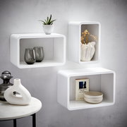 Wandregal-3er-Set in Weiß, bestehend aus drei rechteckigen Regalen, dekoriert mit Pflanzen, Vasen und Büchern, an einer grauen Wand montiert, seitliche Perspektive.