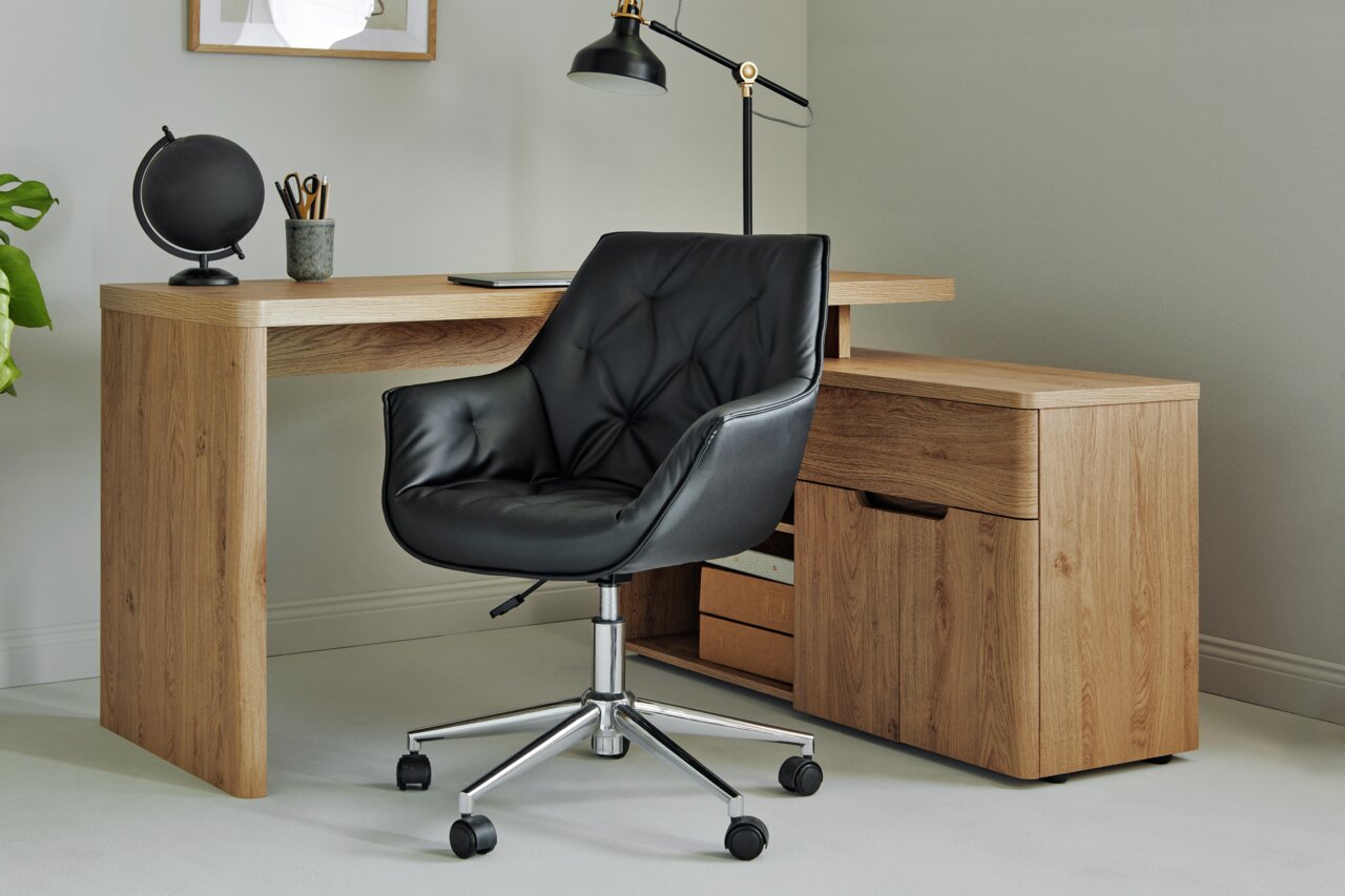 Schwarzer Bürostuhl mit gepolsterter Sitzfläche und Rückenlehne, auf einem verchromten Drehgestell mit Rollen, vor einem Holztisch in einem modernen Büro, seitliche Perspektive.
