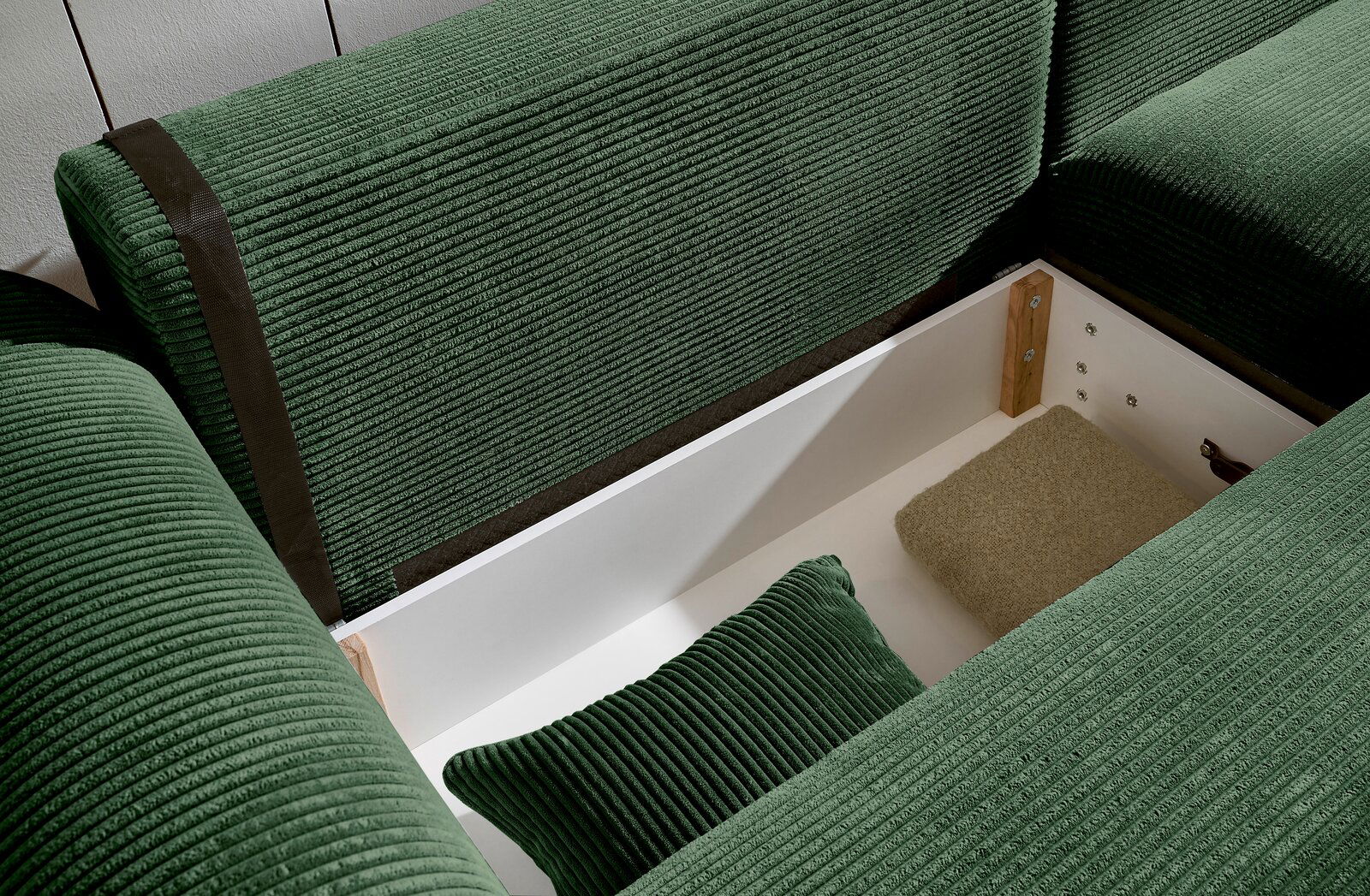 Grüne Rundecke mit Stauraum, von oben betrachtet. Die Polster sind aus geripptem Stoff und es gibt ein Kissen im Stauraum.
