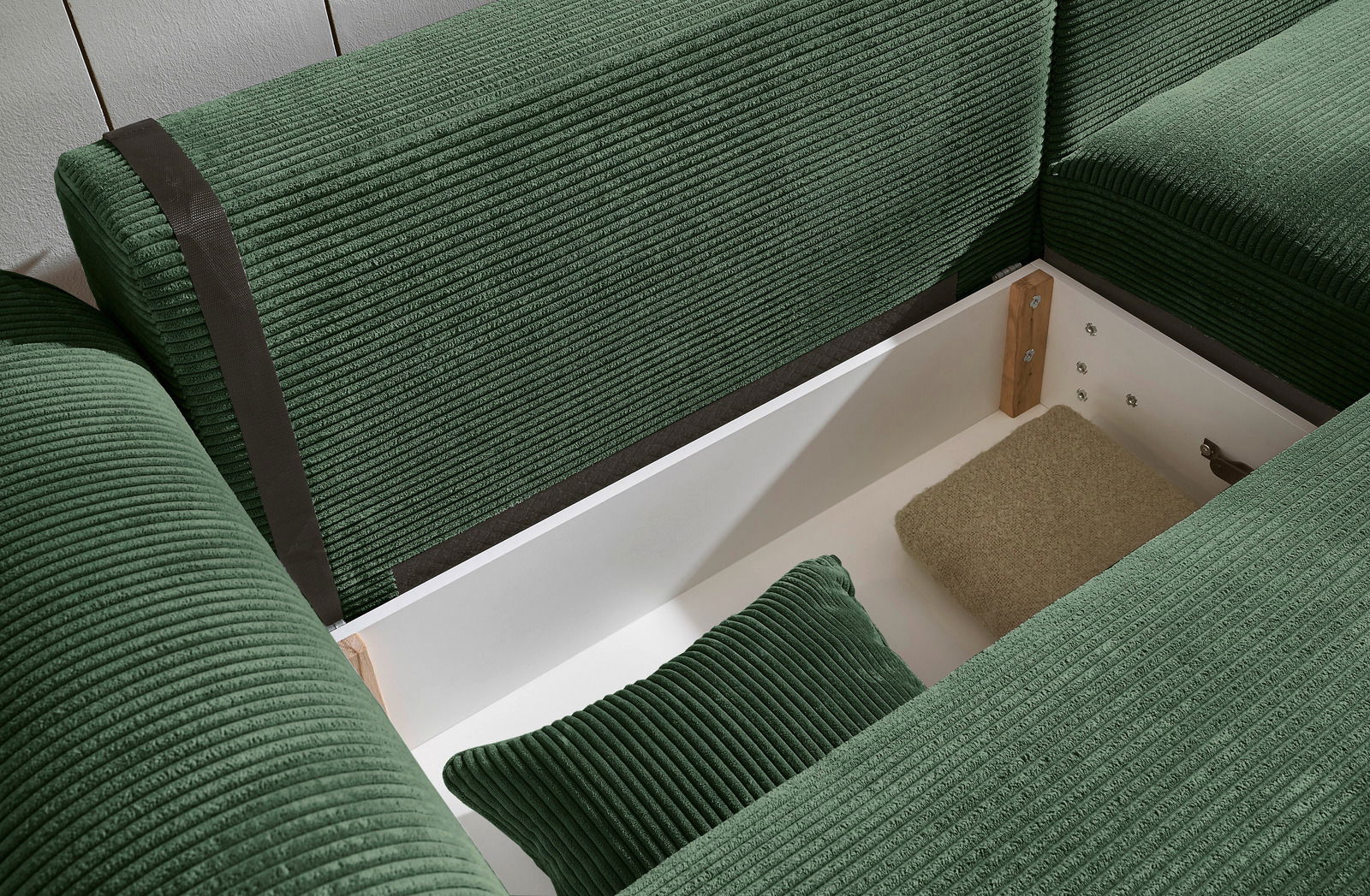 Grüne Rundecke mit Stauraum, von oben betrachtet. Die Polster sind aus geripptem Stoff und es gibt ein Kissen im Stauraum.