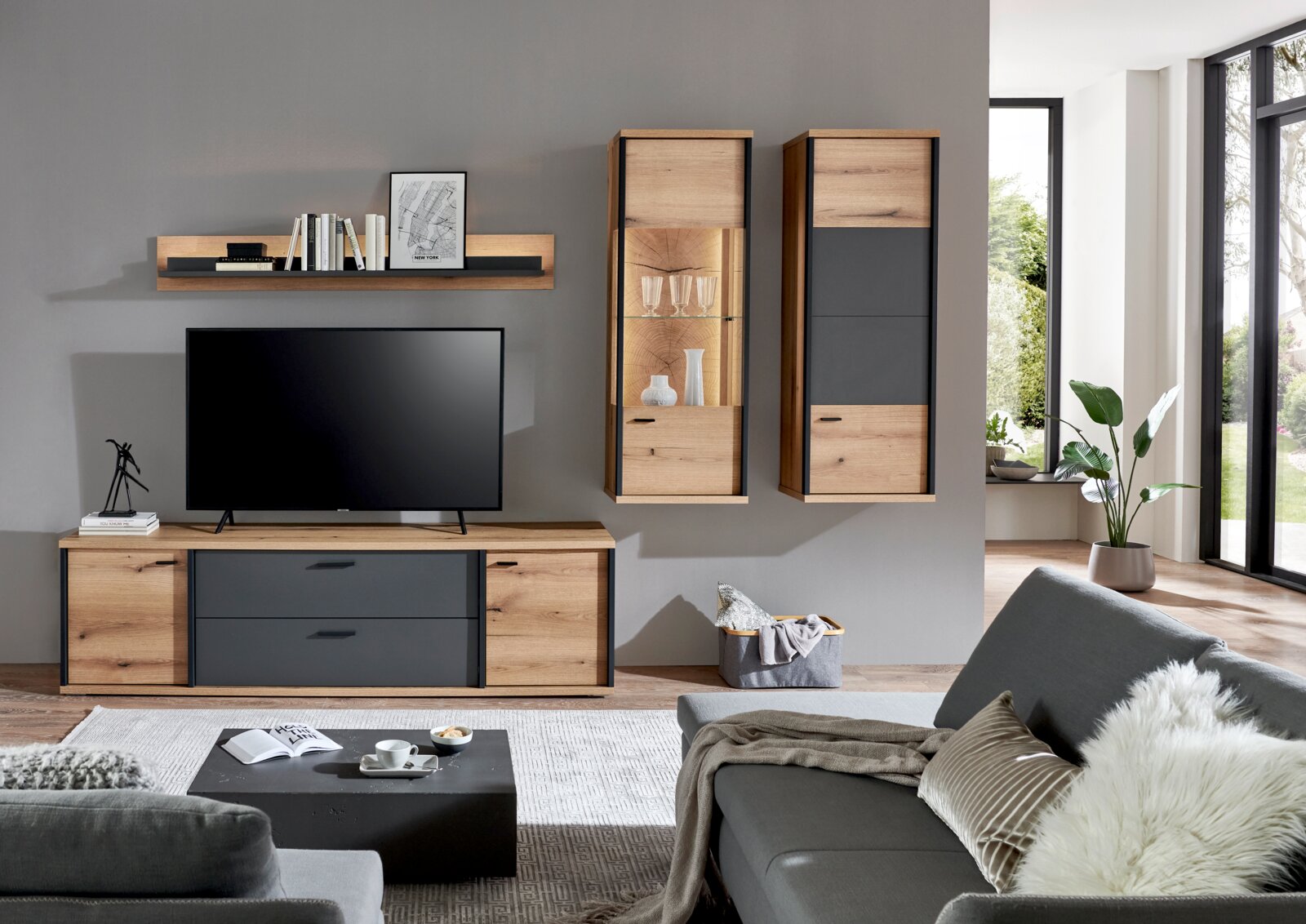 XORA Wandcombinatie MELO Moderne woonkamer met tv-lowboard en wandrek, evenals twee hangende vitrinekasten/hangkasten in eikenlook met antracietkleurige fronten; vooraanzicht van de woonwand tegen een grijze muur.