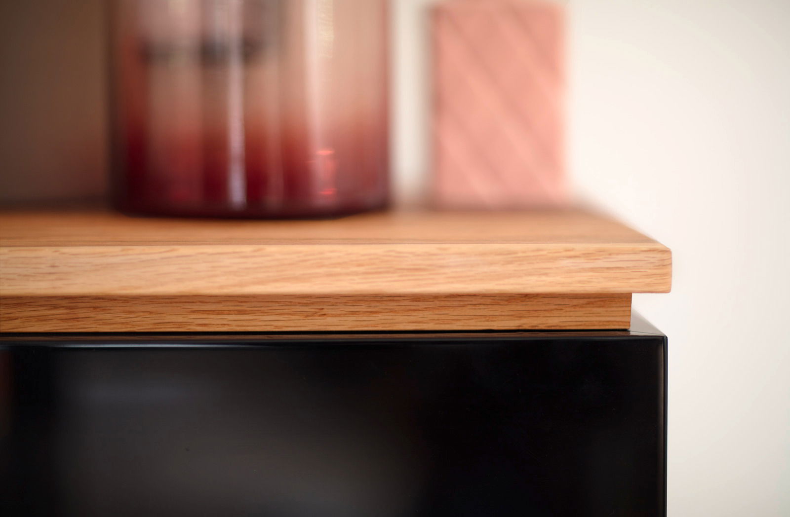 Nahaufnahme eines Möbelstücks mit einer Holzoberfläche und einem schwarzen Element, seitliche Perspektive.