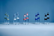 Verschillende drinkflessen in diverse kleuren, vooraanzicht op een tafel tegen een blauwe achtergrond.