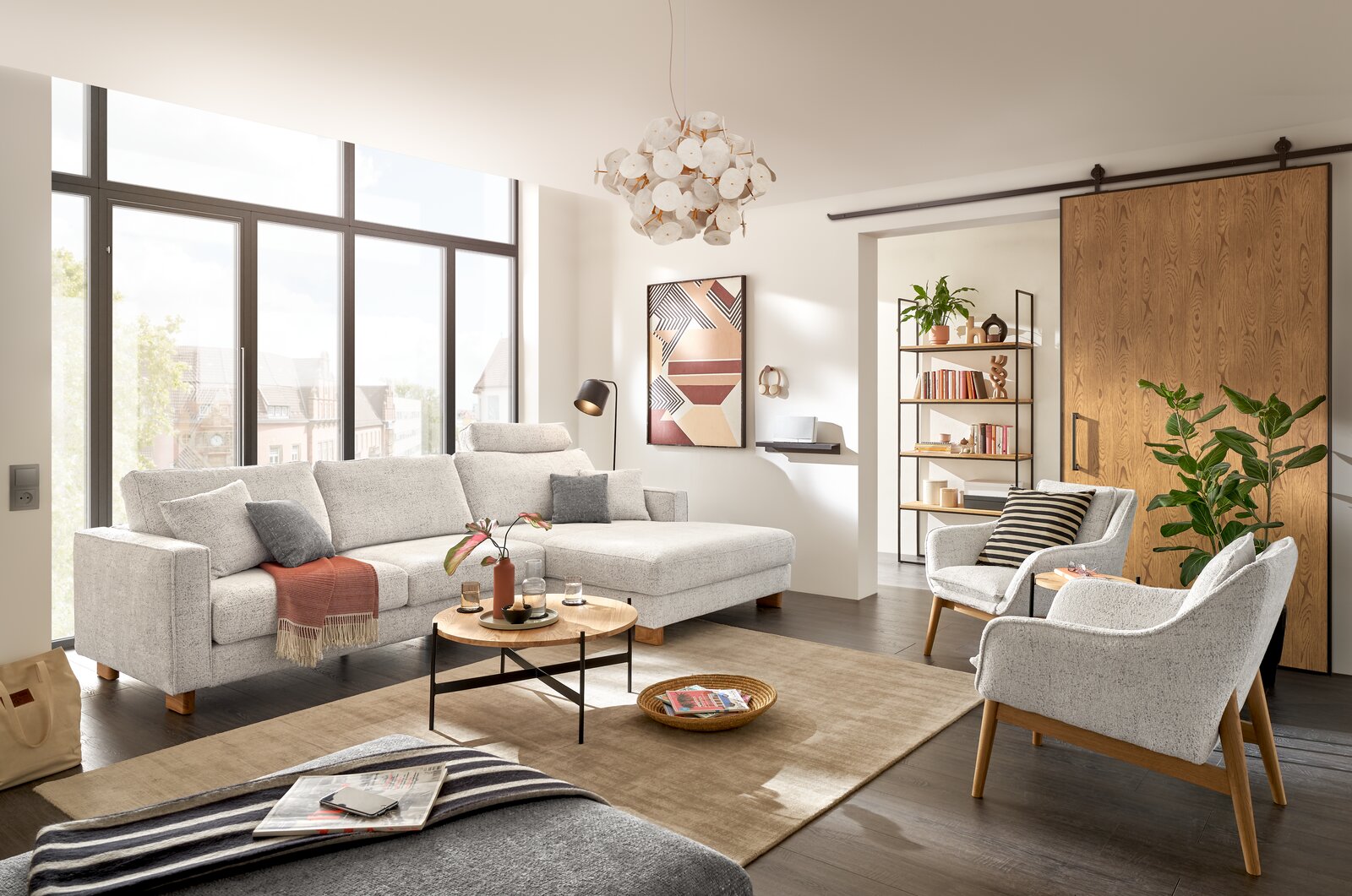 Moderner Wohnraum mit einem hellgrauen Sessel im Vordergrund, umgeben von einem großen Fenster, einem Sofa und einem Couchtisch. Perspektive von vorne.