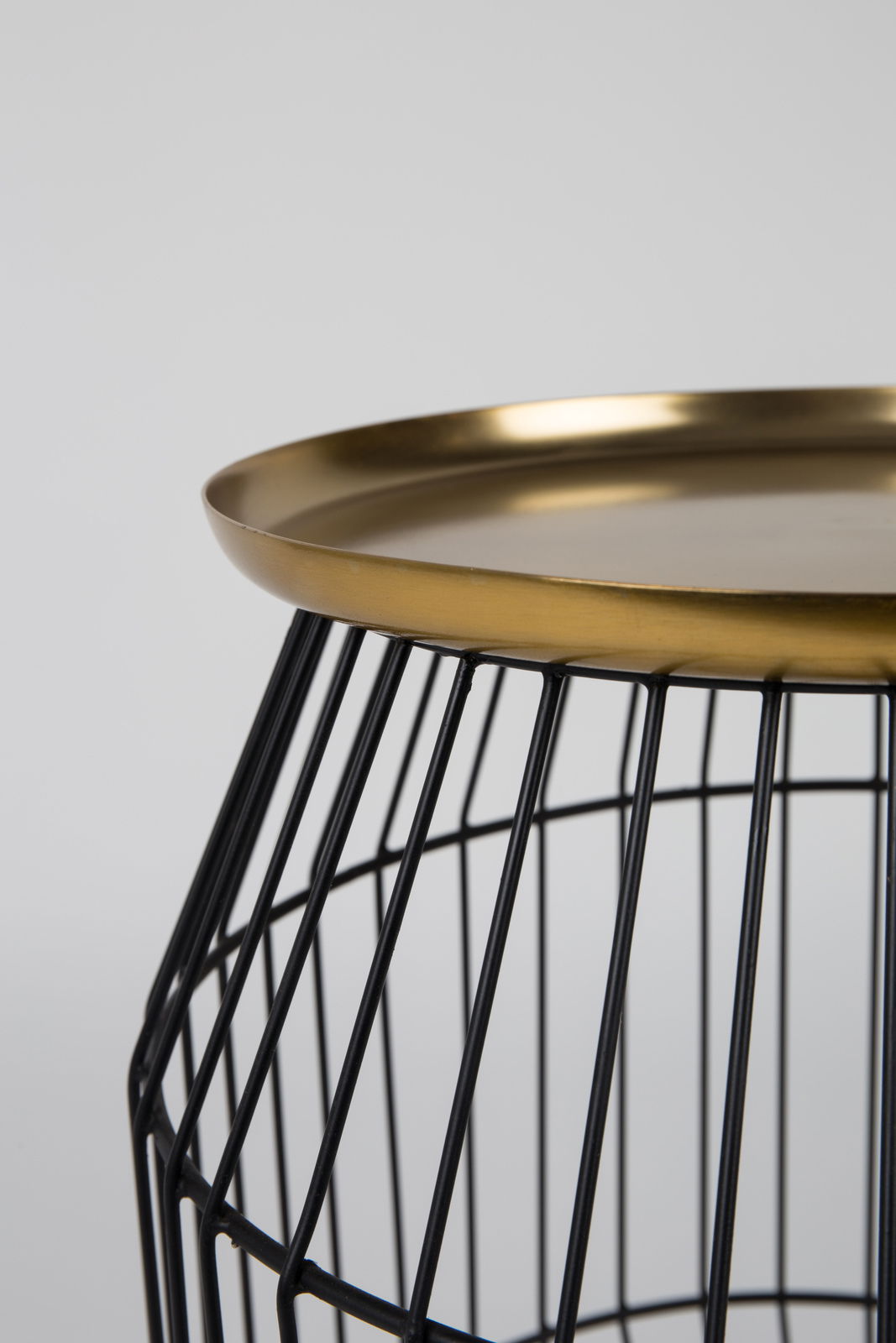 Nahaufnahme eines Beistelltisches mit schwarzem Drahtgestell und goldener Tischplatte, seitliche Perspektive