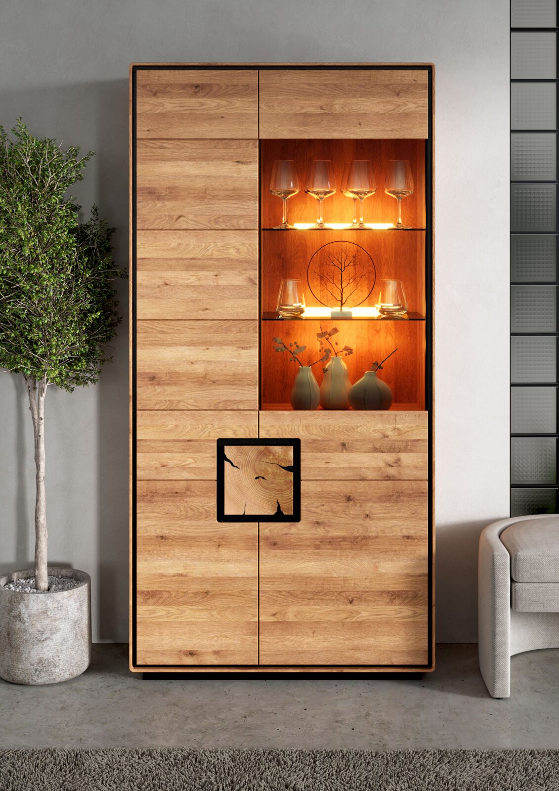Landscape Kombi-Vitrine II BRIXEN Hoher Vitrinenschrank aus hellem Holz mit integrierter, warm beleuchteter Glasvitrine und Deko-Gläsern, frontal aufgenommen.