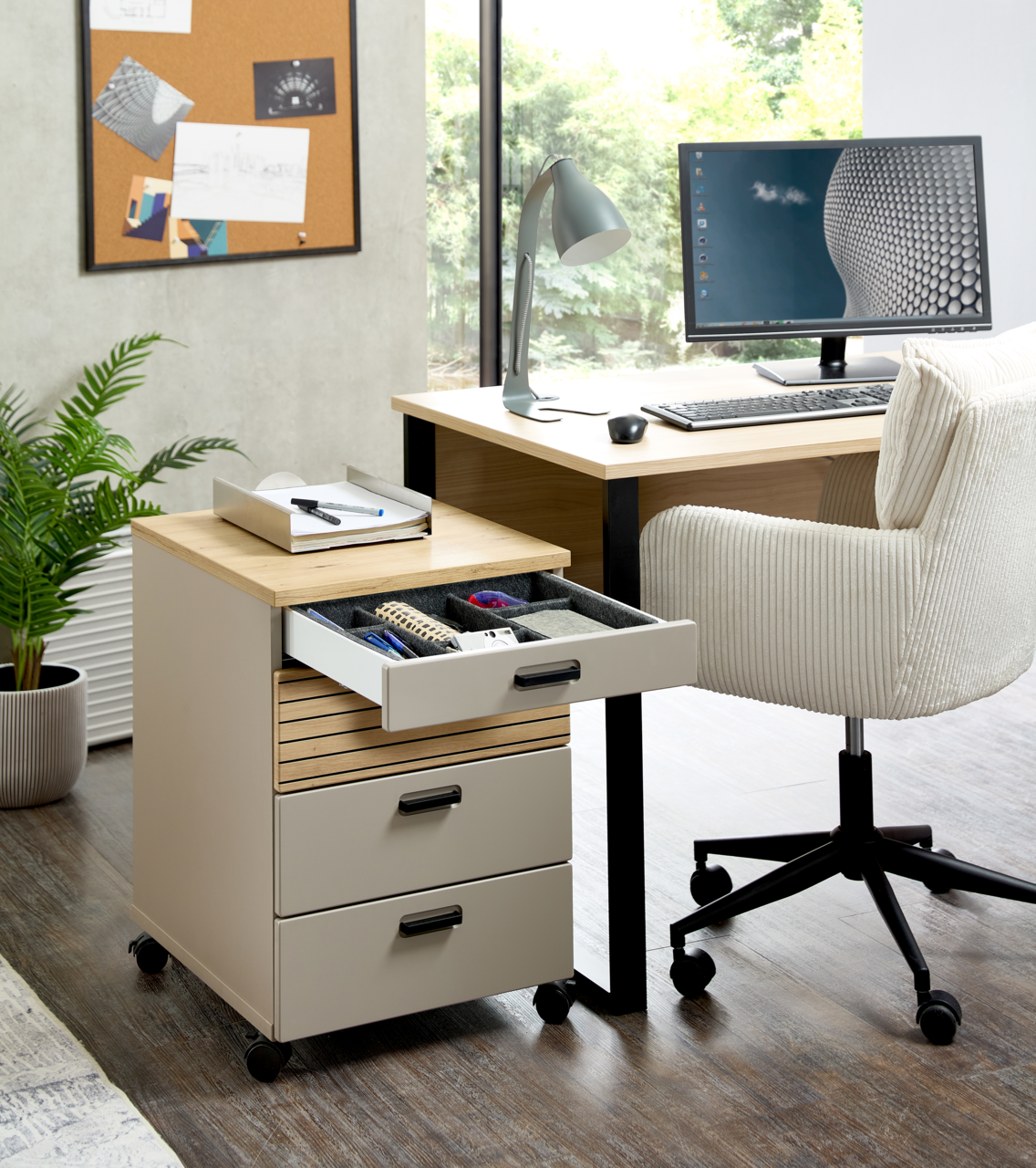 Rollcontainer mit drei Schubladen, teilweise geöffnet, in einem modernen Büro mit Schreibtisch und Stuhl, seitliche Perspektive