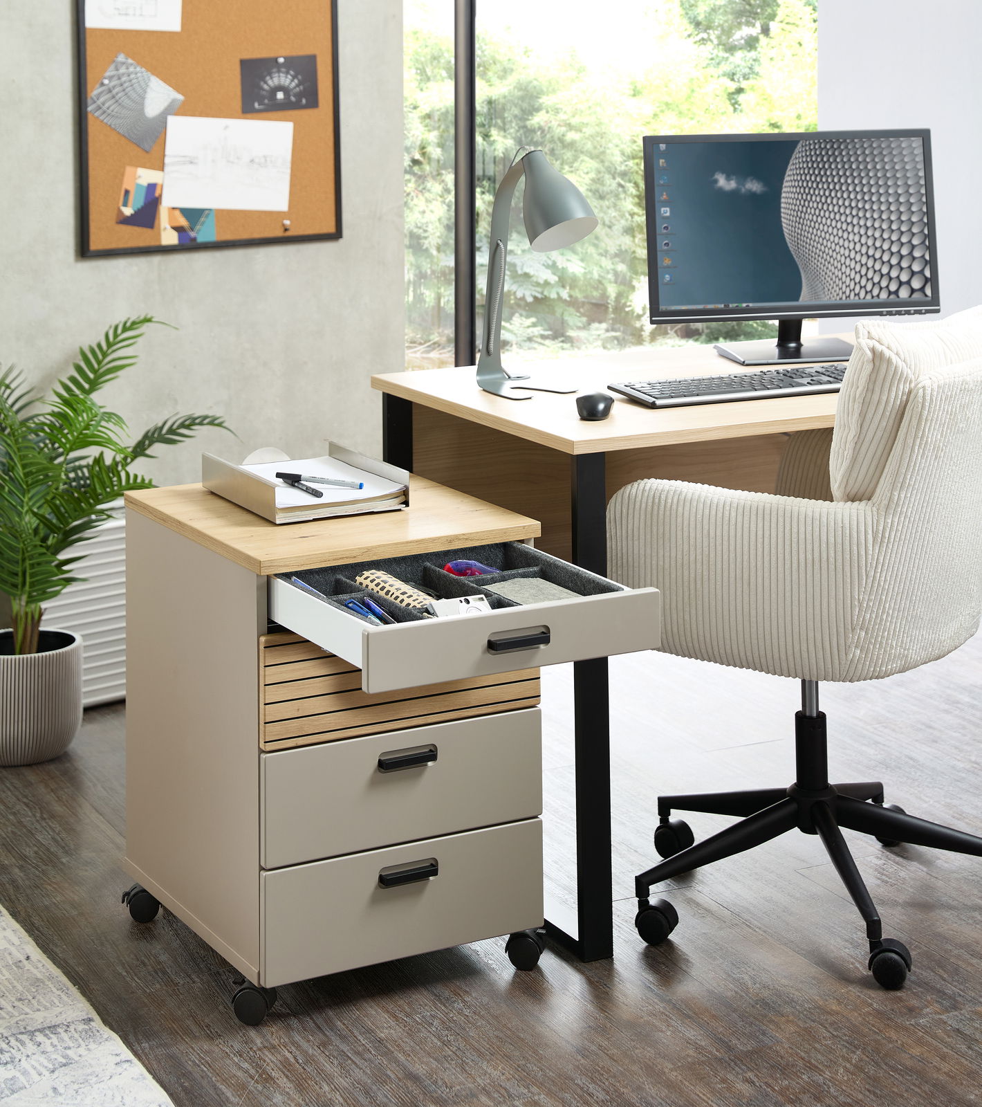 Rollcontainer mit drei Schubladen, teilweise geöffnet, in einem modernen Büro mit Schreibtisch und Stuhl, seitliche Perspektive