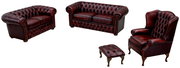 Chesterfield Sitzgarnitur in dunklem Leder, bestehend aus einem 3er-Sofa, einem 2er-Sofa, einem Sessel und einem Hocker, aus einer leicht erhöhten Perspektive fotografiert.