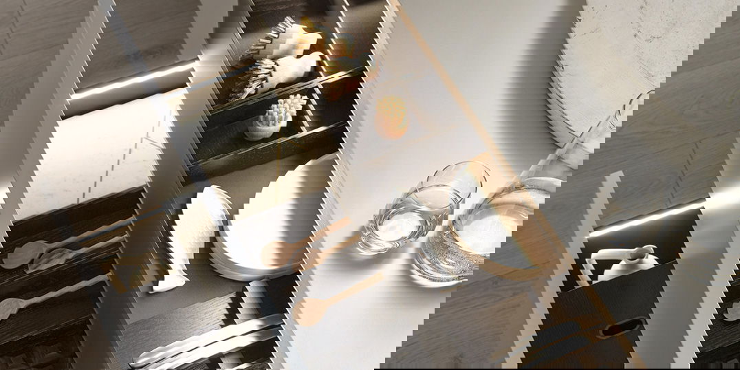 Geöffnete Küchenschubladen mit Holz- und Metallbesteck, Bürsten und LED-Beleuchtung in modernem Design.