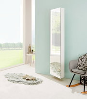 Moderner weißer Drehschuhschrank mit Spiegel, seitliche Perspektive, in einem hellen Raum mit großen Fenstern und stilvoller Dekoration.