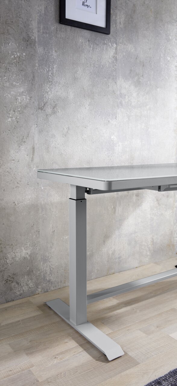 Moderner höhenverstellbarer E-Schreibtisch aus Metall in seitlicher Perspektive, vor einer Betonwand auf Holzboden.
