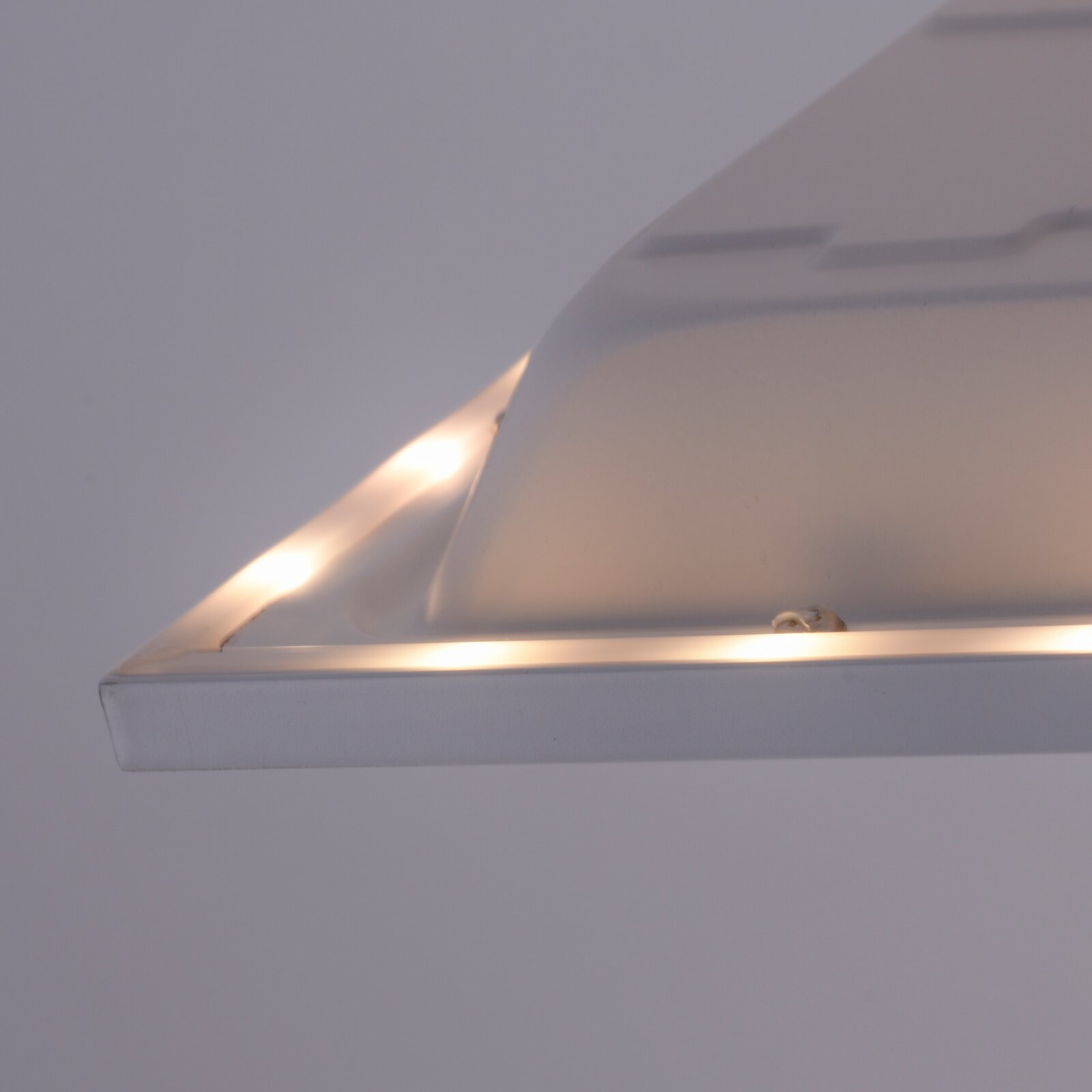 Weiße Deckenleuchte mit abgerundetem, opalem Diffusor und warmem Licht, fotografiert aus seitlicher Untersicht (Nahaufnahme).