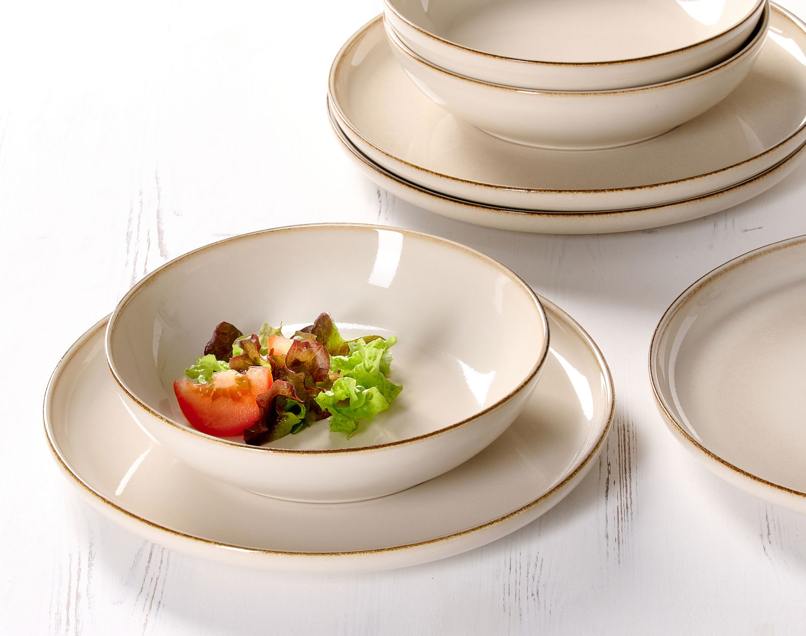 Ritzenhoff & Breker Speiseset 8-tlg. OLIVIA Nahaufnahme eines eleganten, cremefarbenen Speisesets mit Tellern und Schalen, dekoriert mit frischem Salat und Tomaten.